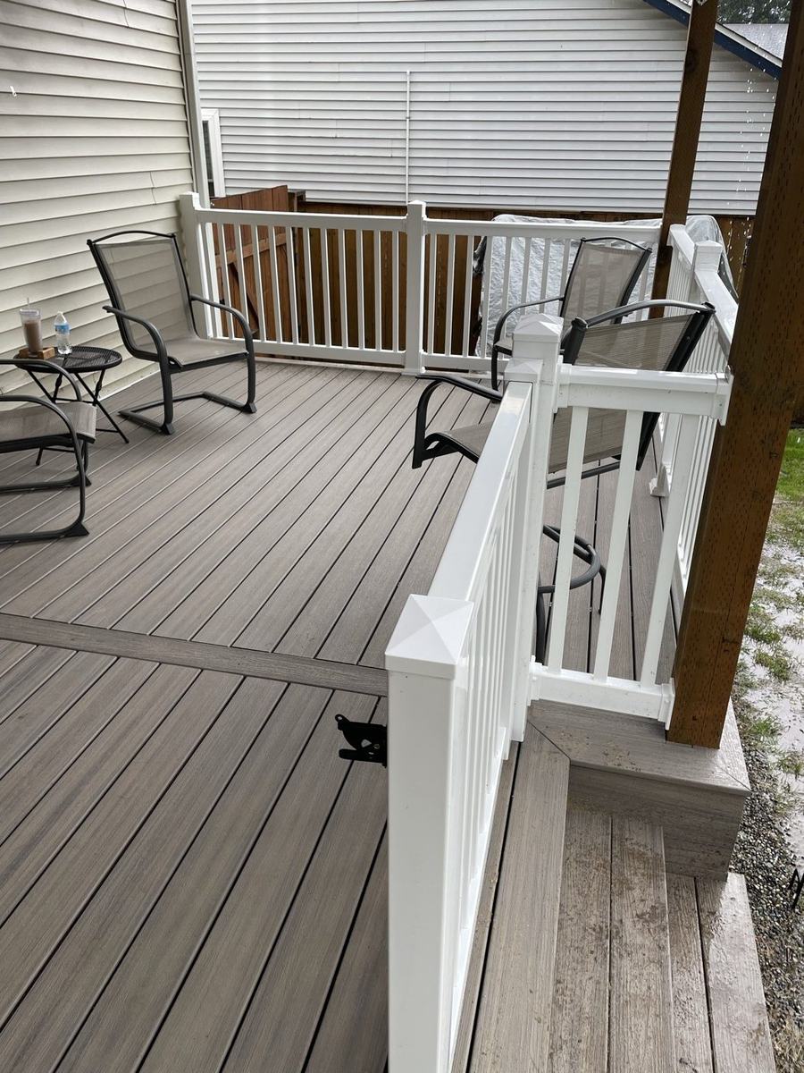 Rebuilt front porch with composite decking and black aluminum railings on a brick ranch home