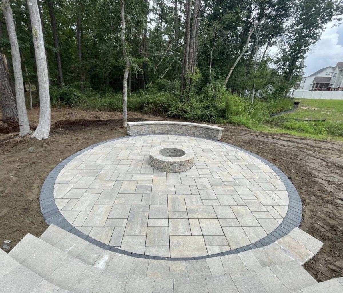 Circular paver patio with stone fire pit and curved seating wall